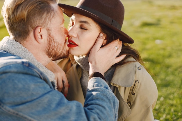 Free photo man and woman in fashion clothes sitting on a nature on a picnic rug. man wearing jacket and woman coat