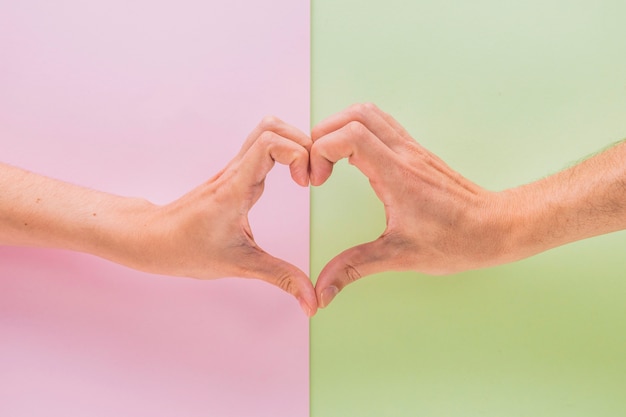 Man and woman hands showing symbol of heart 