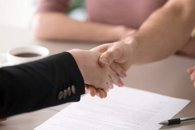 Free photo man and woman handshaking after signing documents, successful deal, closeup