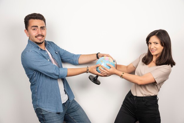 Man and woman holding a globe on white.