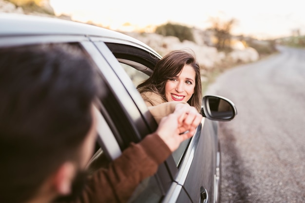 Man and woman holding hands outside of car