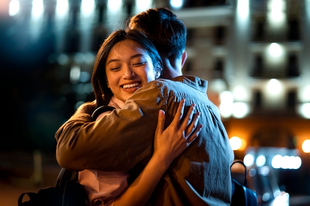 Man and woman hugging at night in the city lights