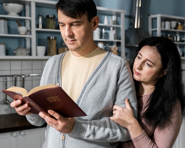 Free photo man and woman in the kitchen reading from the bible