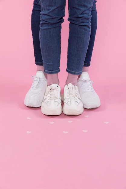 Man and woman legs in jeans and sneakers near decorative hearts 