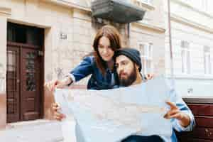 Free photo man and woman look at the map sitting on the bench somewhere in an old city