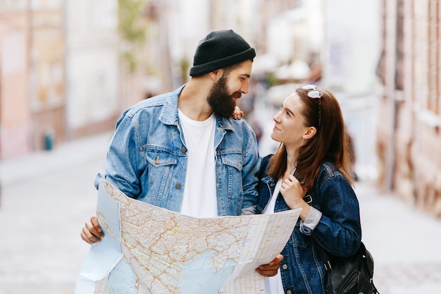 Man and woman look at the map standing somewhere in an old city