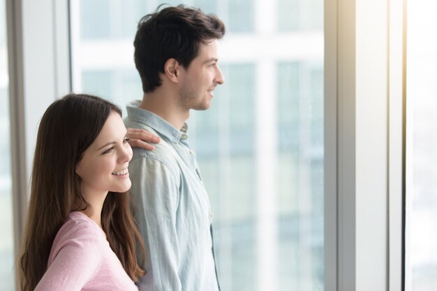 Man and woman looking through window at city scenery