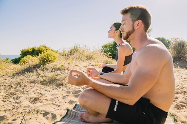 Man and woman meditating at the beach