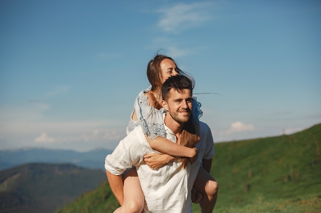 Man and woman in the mountains. Young couple in love at sunset. Woman in a blue dress.