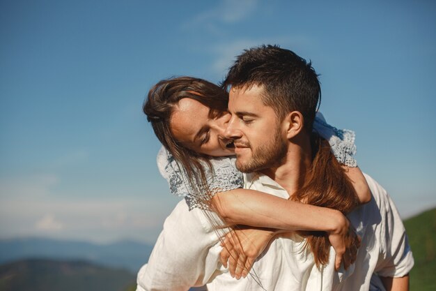 Man and woman in the mountains. Young couple in love at sunset. Woman in a blue dress.