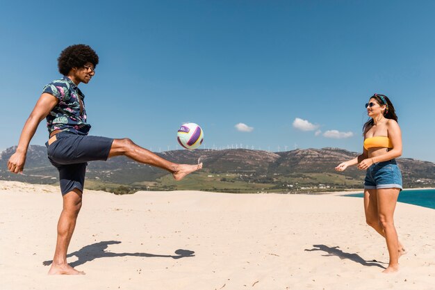 Man and woman playing soccer on sand beach