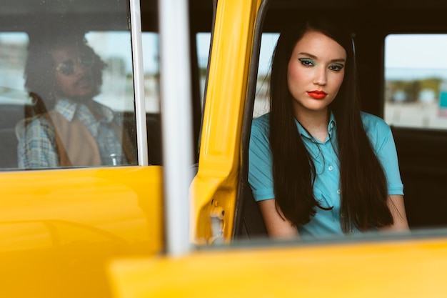 Man and woman posing in retro style with car