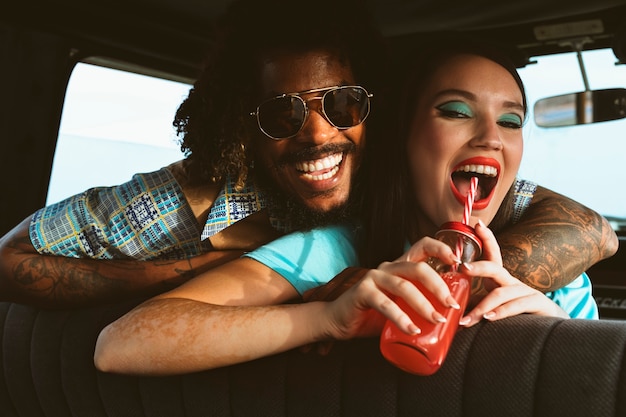 Free photo man and woman posing together in retro style inside vehicle with juice