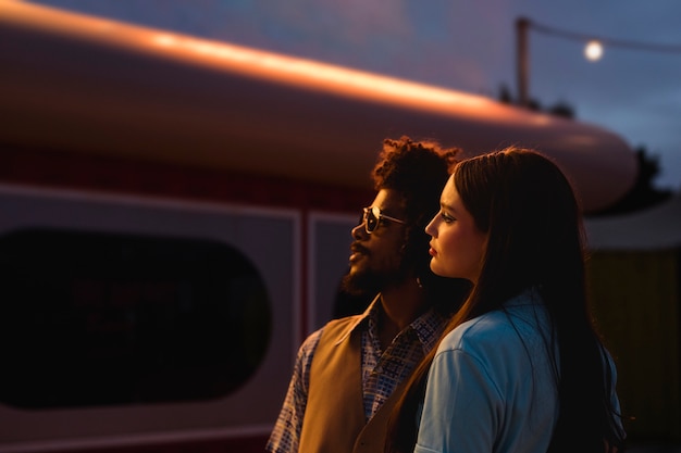 Man and woman posing together in retro style at night with lights