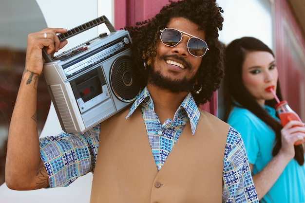 Man and woman posing together in retro style with radio player and juice