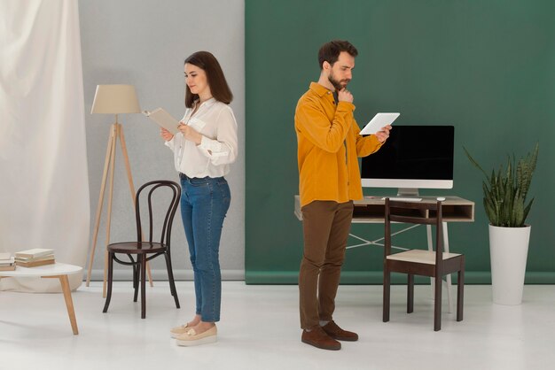 Man and woman reading books and using tablet