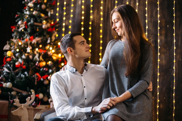 Man and woman rest before a Christmas tree in a cosy room