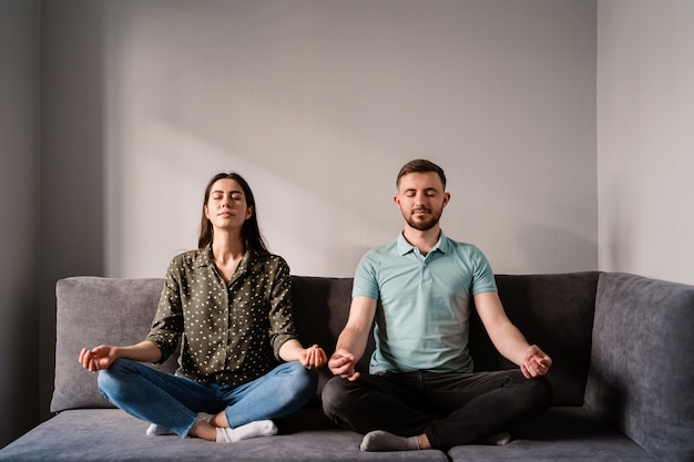 Man and woman sitting on sofa in lotus pose