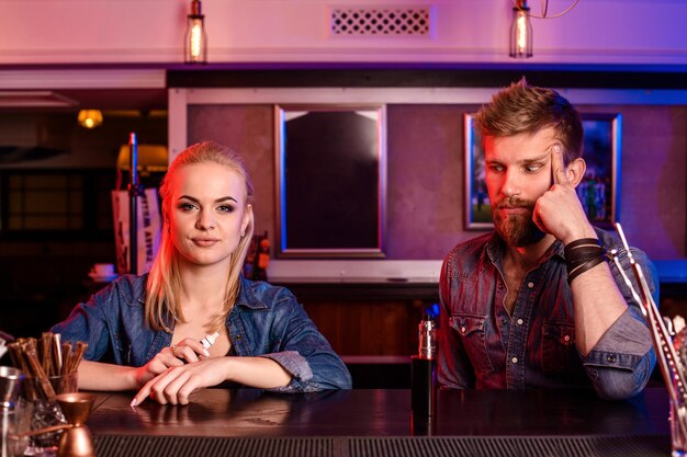 A man and woman smoking electronic cigarette in a vape bar.