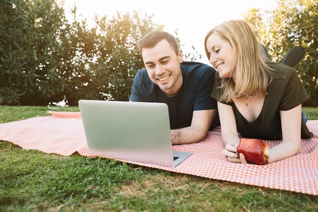 Man and woman using laptop on picnic