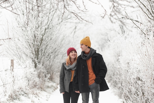 Free photo man and woman walking in the winter forest