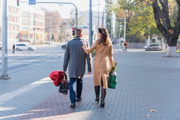 Free Photo man and woman with bags going on street