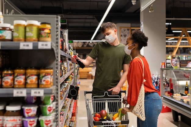 Man and woman with medical masks out grocery shopping with shopping cart