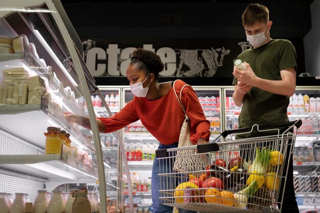 Man and woman with medical masks out grocery shopping with shopping cart