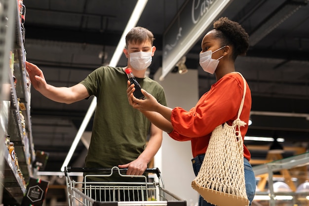 Man and woman with medical masks out grocery shopping with shopping cart