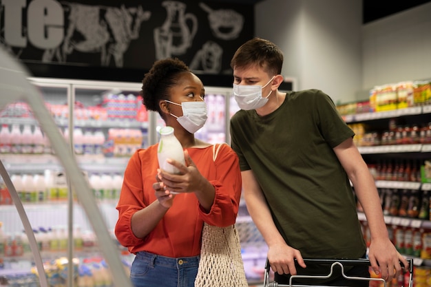 Man and woman with medical masks out grocery shopping with shopping cart