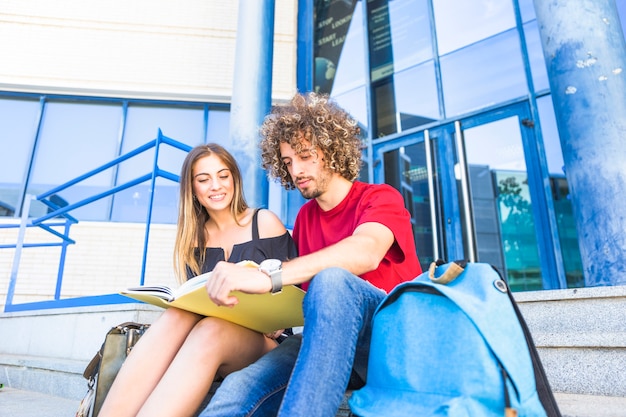 Free photo man and woman with textbook near university