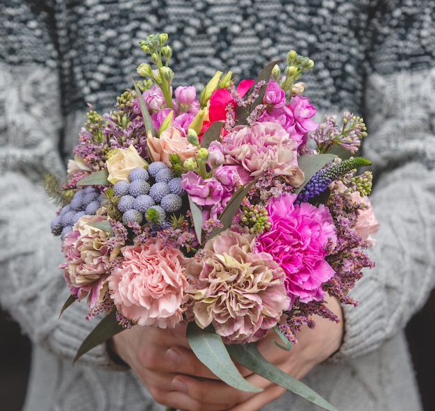 Free photo man in wool sweater holding a bouquet of mixed flowers