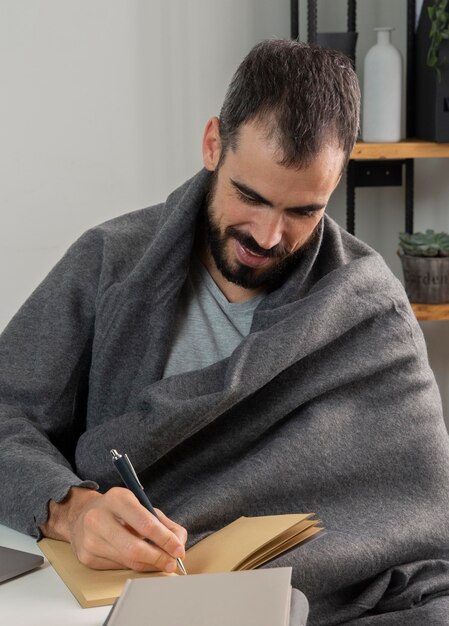 Man working from home and writing in notebook