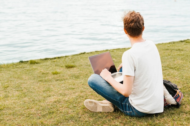 Free Photo man working on laptop by the lake