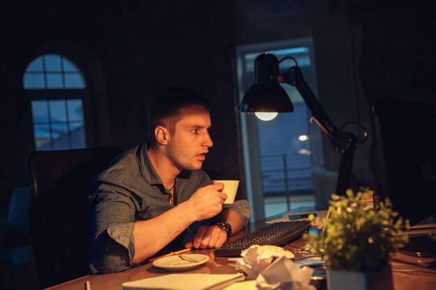 Man working in office alone during coronavirus quarantine staying to late night