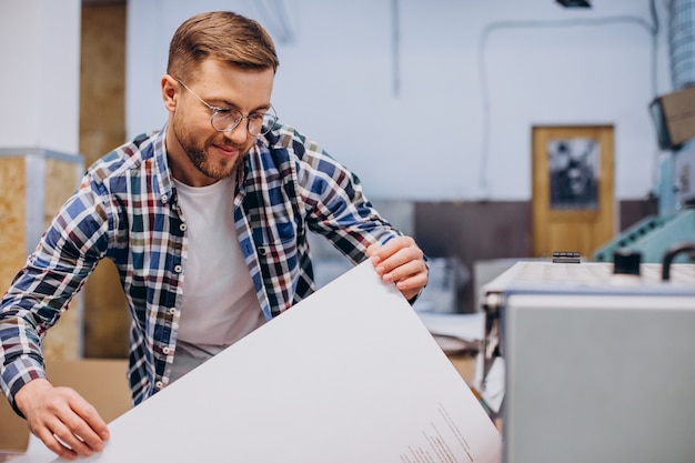 Man working in printing house with paper and paints