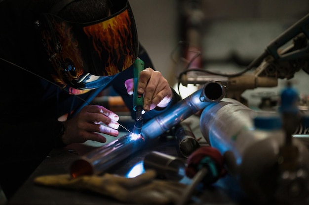 Man working with argon welding machine in a garage