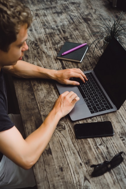 Free photo man working with a laptop in a cafe on a wooden table