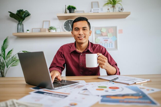 Man working with laptop and holding coffee cup