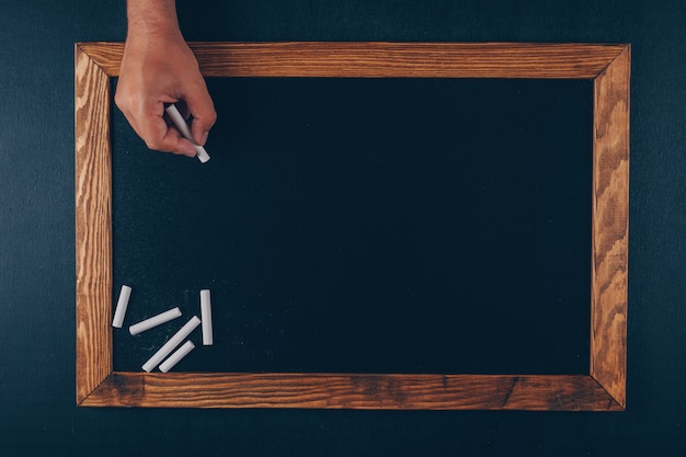 Free photo man writing something with chalk top view on a frame and black