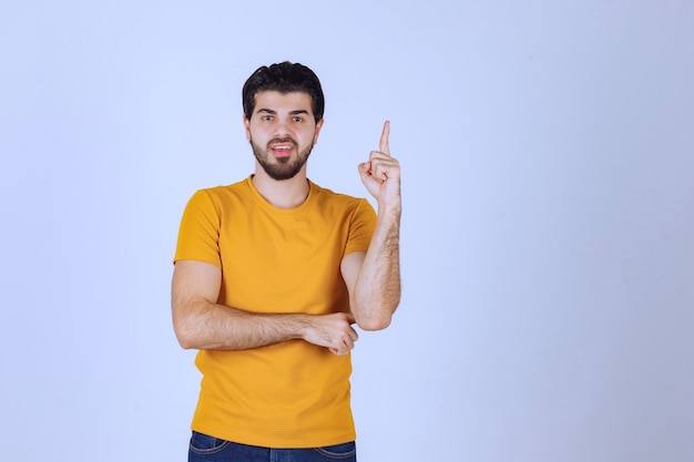 Man in yellow shirt looks doubtful and thinking.