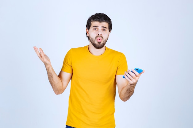 Man in yellow shirt pointing his smartphone and enjoying it.