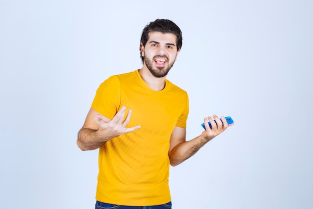 Man in yellow shirt pointing his smartphone and enjoying it.