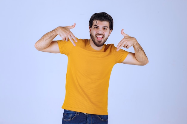 Free photo man in yellow shirt showing gun sign in the hand