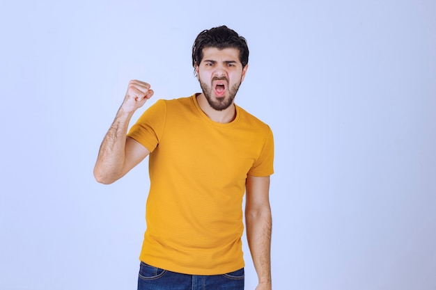 Man in yellow shirt showing his fist and power. 