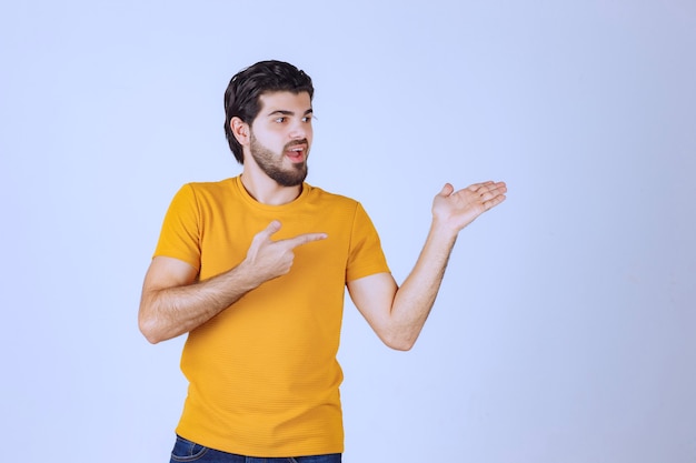 Man in yellow shirt showing something on the right.