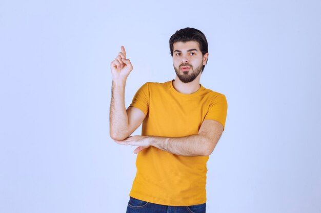 Man in yellow shirt showing something above.