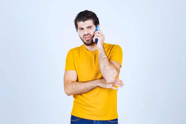 Man in yellow shirt talking to the phone.