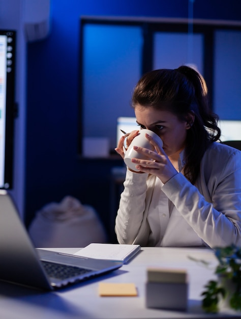 Manager having internet videocall conference sitting in professional start-up business office drinking cup of coffee