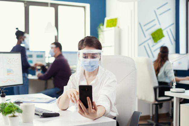 Free Photo manager using smartphone for online conference wearing face mask against covid-19 as safety precaution